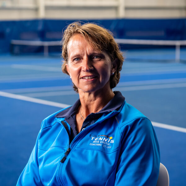 Marijke Nel sitting with tennis courts in background.